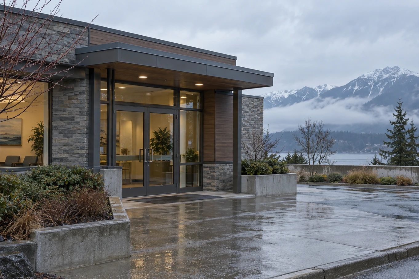 Building entrance beside wet pavement, with mountains in the background.