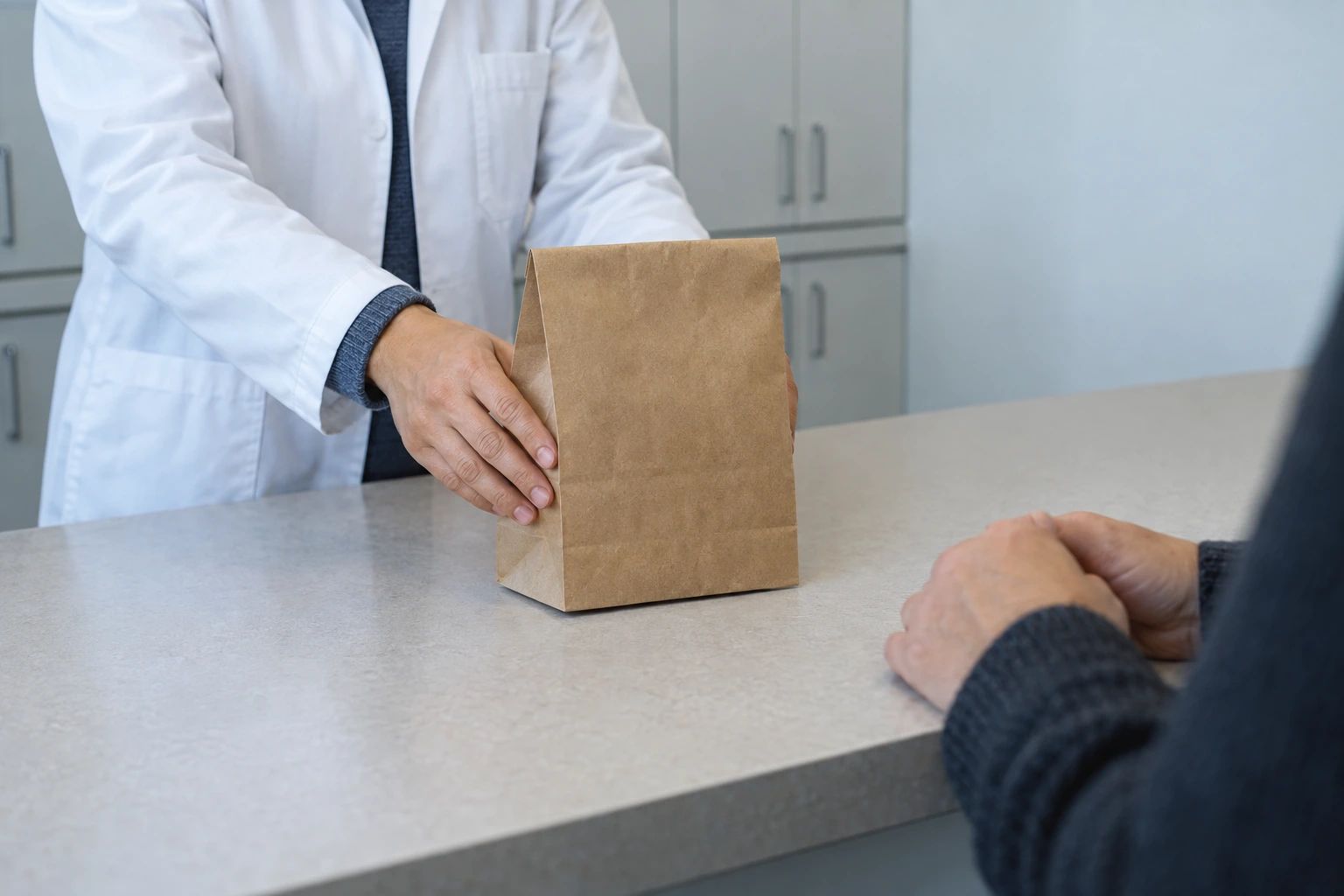 Hands placing a plain paper bag on a counter.